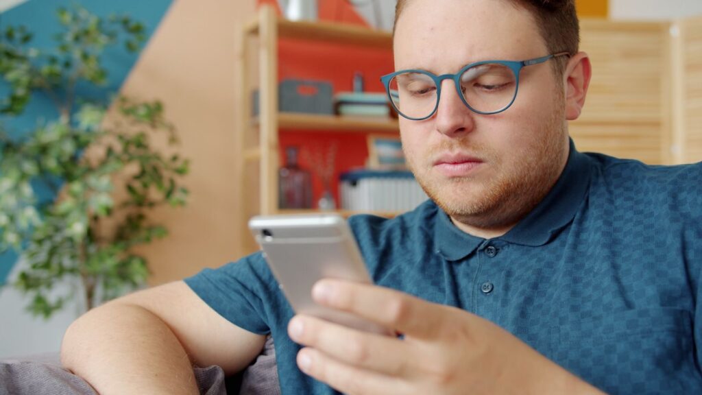 Mężczyzna czyta wpis na smartfonie, naturalny wzrost linków po udanej publikacji